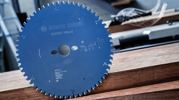 Object #200585337: 7557712_app_web_02 Circular saw blade positioned upright on stacked wooden planks.
