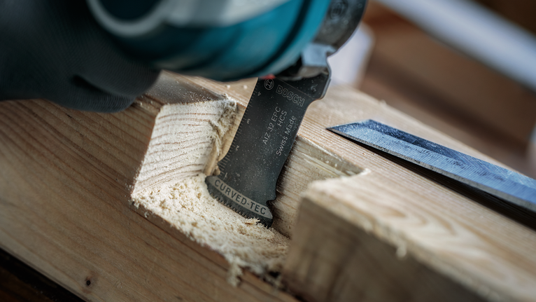 Person wearing safety equipment using a power tool to cut a groove in wood.