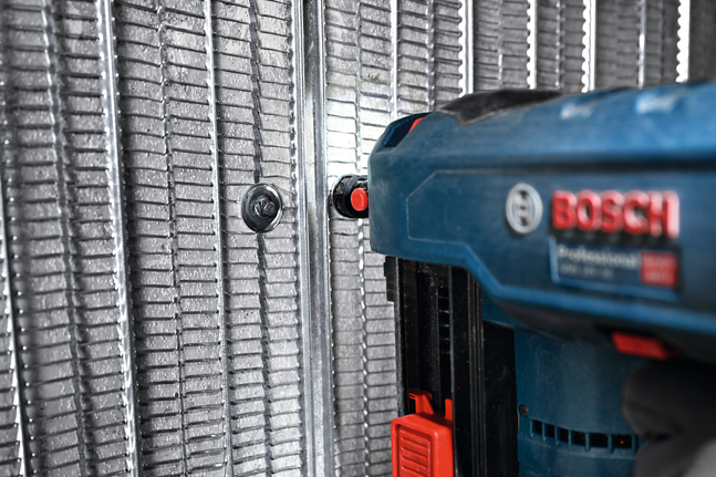 Power tool fastening a PRO FMW-25 Universal Metal Washer onto a metal frame.