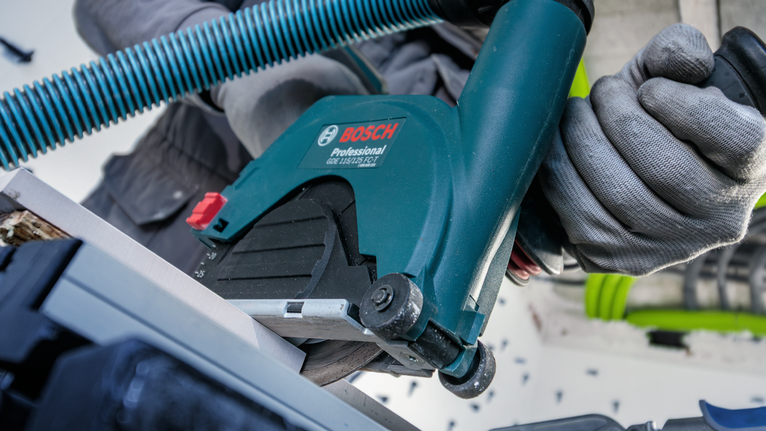 Person wearing safety equipment cuts material with a circular saw.