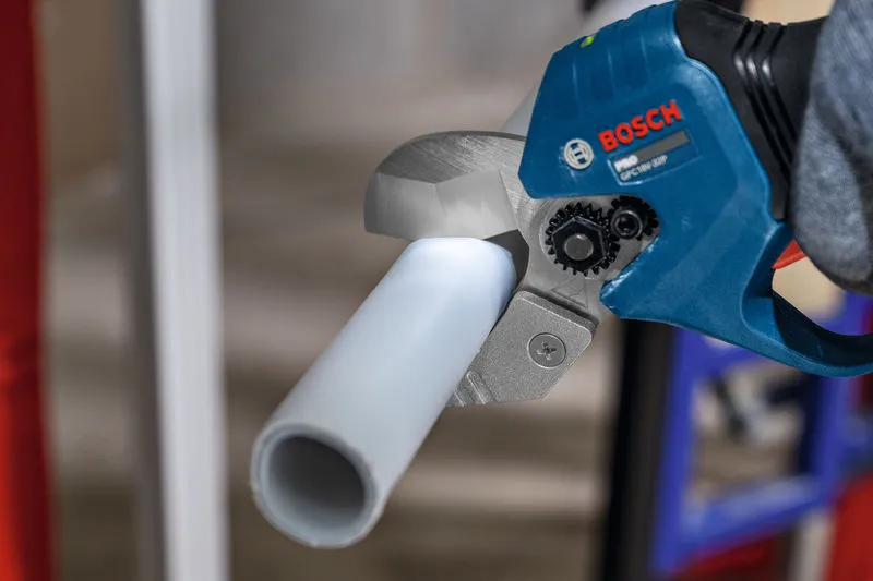 A person uses a cordless pipe shear to cut a plastic pipe.