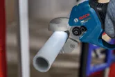 A person uses a cordless pipe shear to cut a plastic pipe.