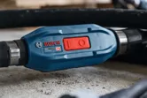Close-up of a blue power tool switch marked GDI59-500 resting on a concrete surface.