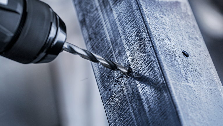 Power drill making a hole in a metal beam.