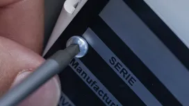 Person using a screwdriver to tighten a screw on a machine label.