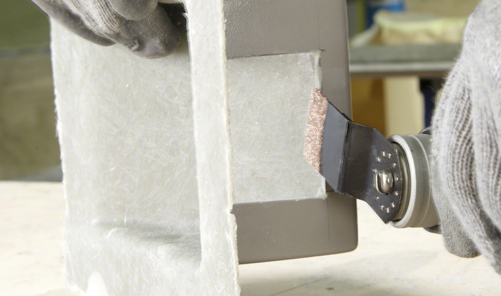 Plunge Cut Saw Blade AIZ 32 RT5 Grout & Abrasive Worker wearing safety equipment uses a multi-tool to cut a panel edge.