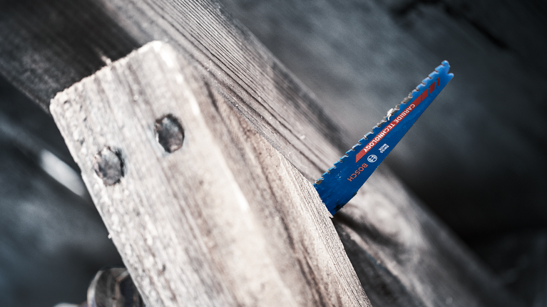 Saw blade cutting through a thick wooden plank.