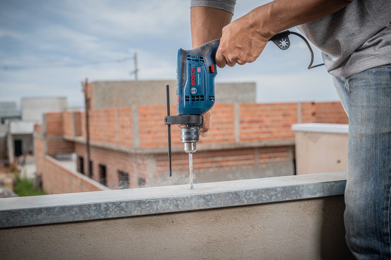 A person drills into concrete at a construction site.