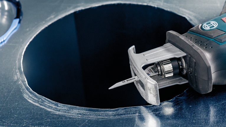 Jigsaw cutting a circular hole in a metal sheet.