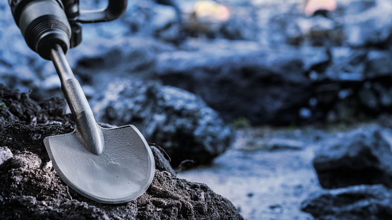 Rotary hammer with a spade chisel breaks through rocky ground.
