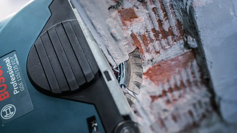 A power tool with a diamond blade cuts a groove into a brick wall.