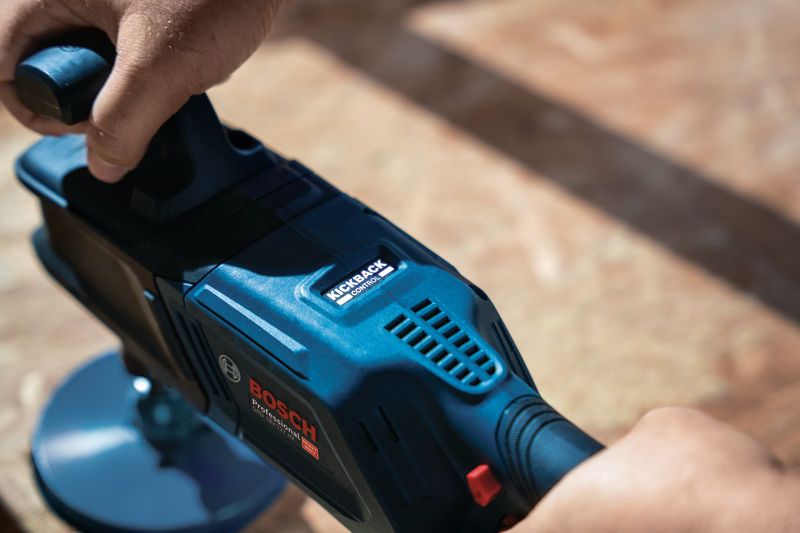 A person operates a cordless angle drill on a wooden surface.