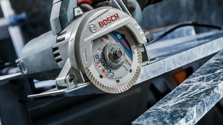 Una persona que usa equipo de seguridad corta una losa de mármol con una sierra circular.