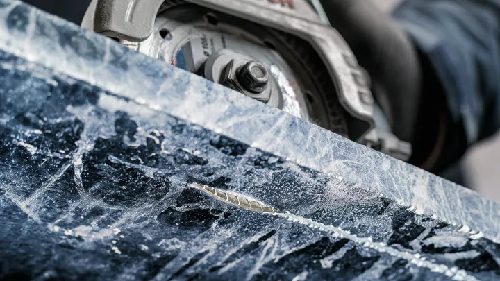 Una persona que usa equipo de seguridad utiliza una sierra circular para cortar piedra.