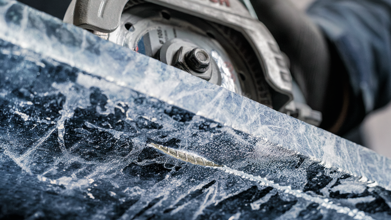 Una persona que usa equipo de seguridad utiliza una sierra circular para cortar piedra.