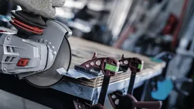 Una persona que usa equipo de seguridad utiliza una amoladora angular para cortar metal fijado a un banco de trabajo.