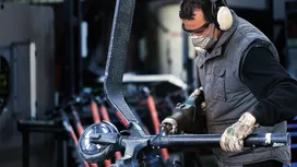 Persona con equipo de seguridad utilizando una herramienta eléctrica para cortar tuberías de metal.
