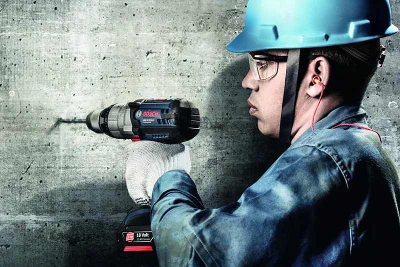 Trabajador perforando muro de hormigón.