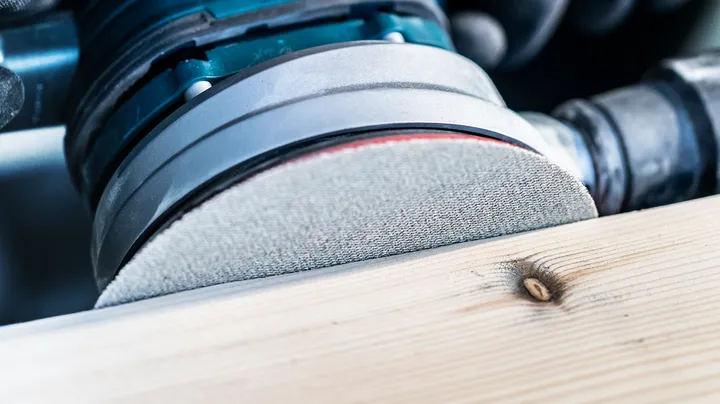 Lijadora eléctrica alisando una superficie de tablón de madera.