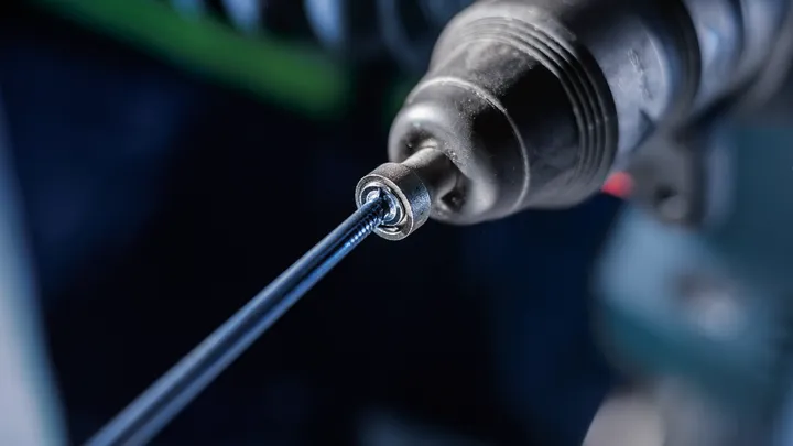 Primer plano de un taladro eléctrico que introduce un tornillo en una superficie.