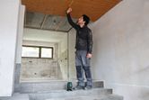 Una persona que lleva equipo de seguridad mide un techo utilizando un nivel láser.