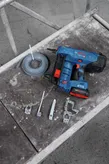 Clavadora de hormigón inalámbrica y accesorios de montaje colocados sobre un banco de trabajo.