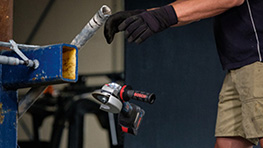 Un operario con guantes sostiene un destornillador Bosch Professional sobre una mesa de trabajo.