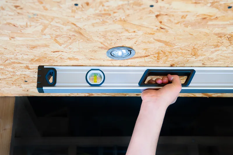 Person holding an optical level tool against a wooden ceiling.