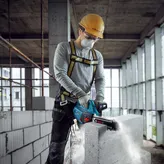 A person wearing safety equipment cuts an AAC block with a power cutter.