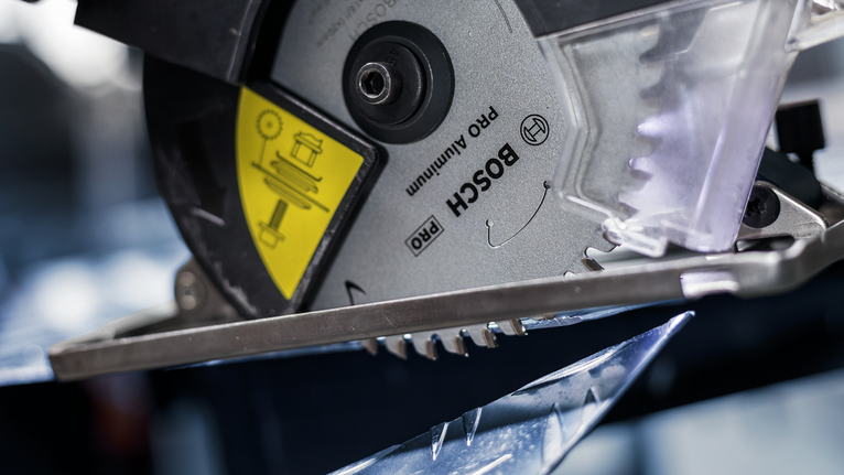 Circular saw blade cutting through a sheet of metal.