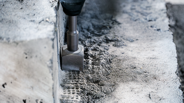Demolition hammer chiseling concrete surface.