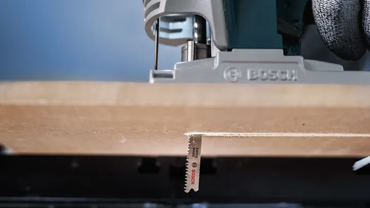 Jigsaw cutting a precise straight line through a wooden board.
