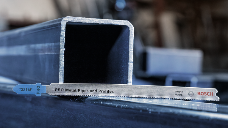 Saw blade for cutting metal pipes and profiles placed beside a metal channel.