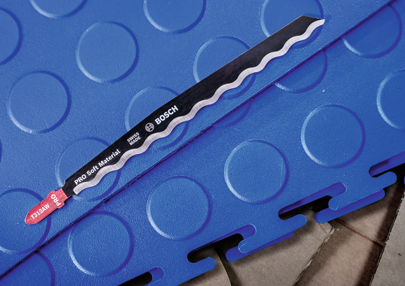 Jigsaw blade placed on interlocking blue foam flooring.