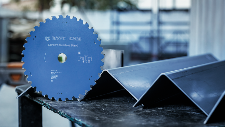 Circular saw blade placed on a table beside angled metal beams.