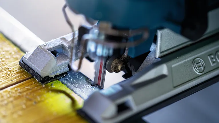 Jigsaw cutting through a wooden board, producing fine sawdust.