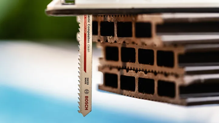 Jigsaw blade cutting through stacked hollow composite material.