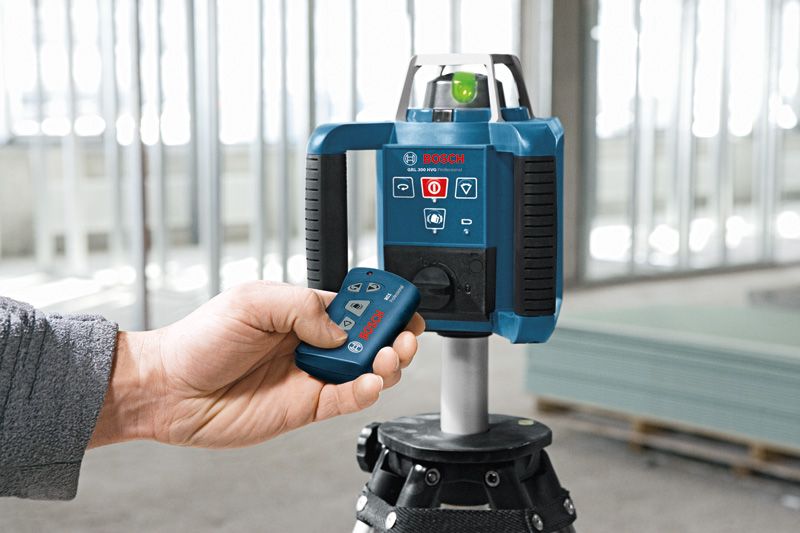 Person operates a laser leveling tool with a remote in a construction setting.