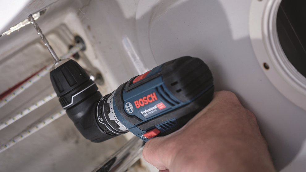 Czarny wiertarko-wkrętarka Bosch Professional trzymana w ręce, wierci w białej powierzchni.