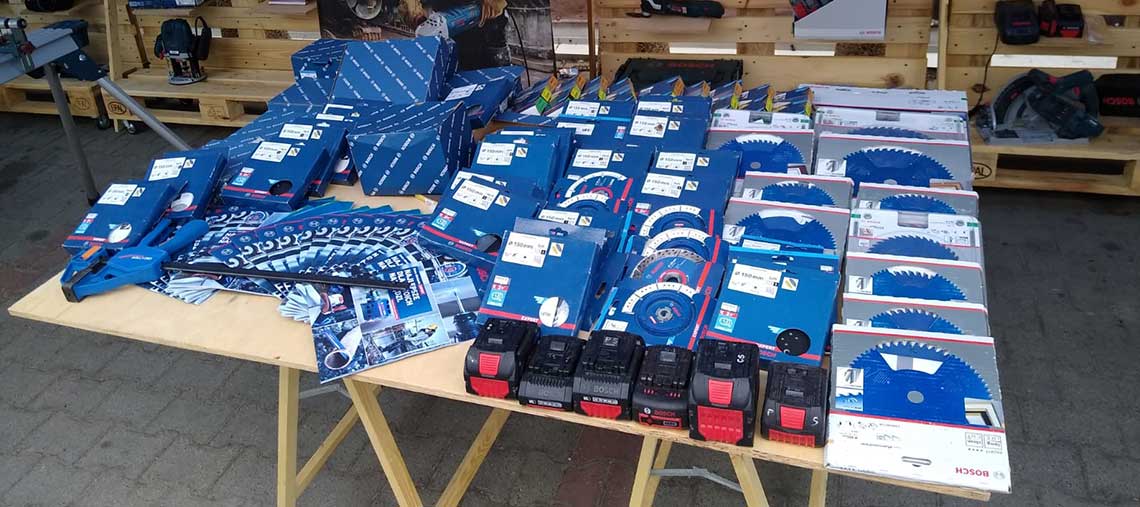 Stół z narzędziami Bosch Professional, niebieskie opakowania i akcesoria w rządach.