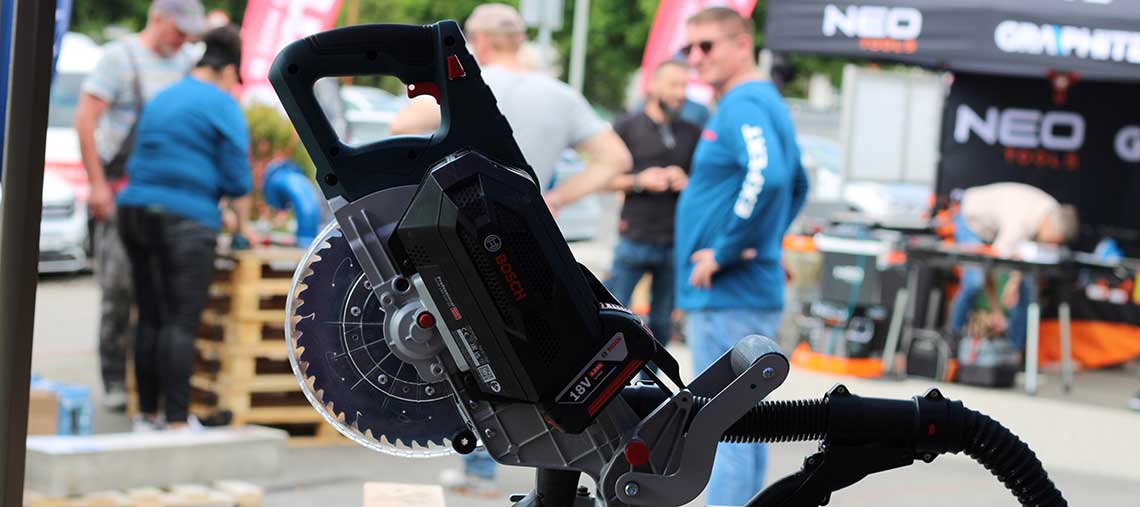 Czarna piła tarczowa Bosch Professional na tle ludzi i stoiska z narzędziami.