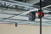 Urządzenie do poziomowania laserowego wyświetlające linie na kratownicy sufitu podwieszanego w celu jego wyrównywania.