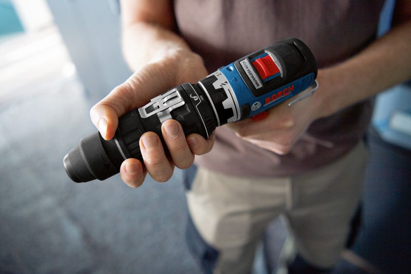 Osoba trzyma adapter FlexiClick do elektronarzędzia w pomieszczeniu.