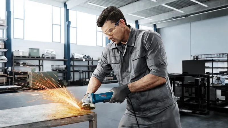 Mężczyzna szlifujący metalowy stół.