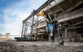 Pracownik używa młota pneumatycznego na miejscu budowy.