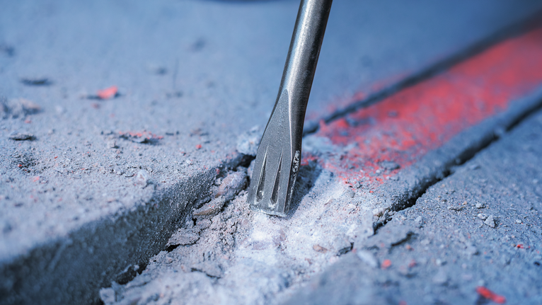 Dłuto rozbijające beton wzdłuż zaznaczonej linii.