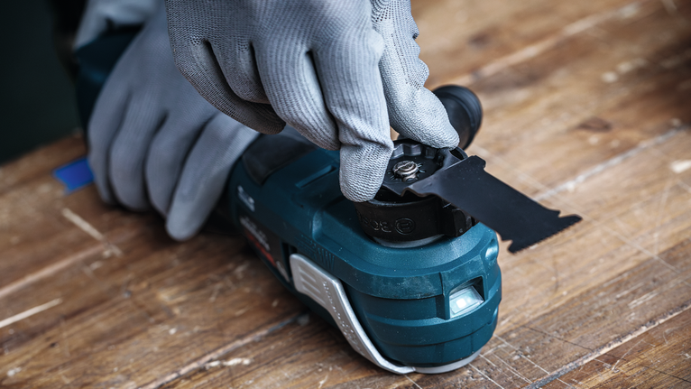 Osoba ubrana w sprzęt ochronny mocuje ostrze piły do elektronarzędzia.