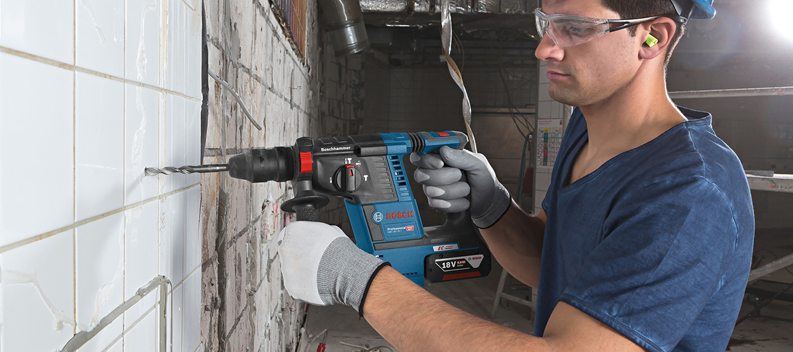 Homem usando um martelete Bosch Professional em azulejos brancos.