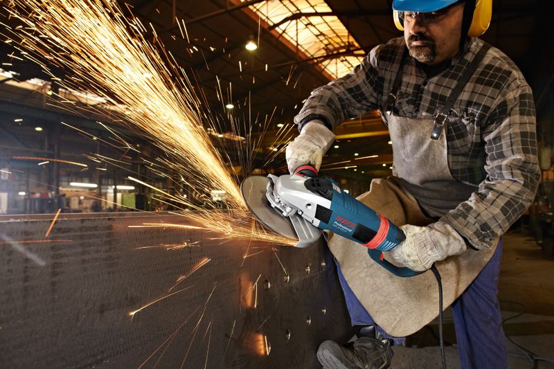 Uma pessoa que usa equipamento de segurança tritura metal, criando uma chuva de faíscas brilhantes.