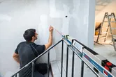 Uma pessoa marca uma parede utilizando um inclinómetro digital projetando uma linha reta laser.